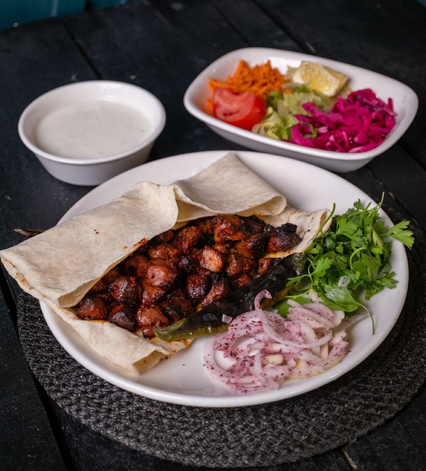 Lavaş üzerinde ciğer porsiyon, maydanoz, sumaklı soğan, yanında ayran ve salata