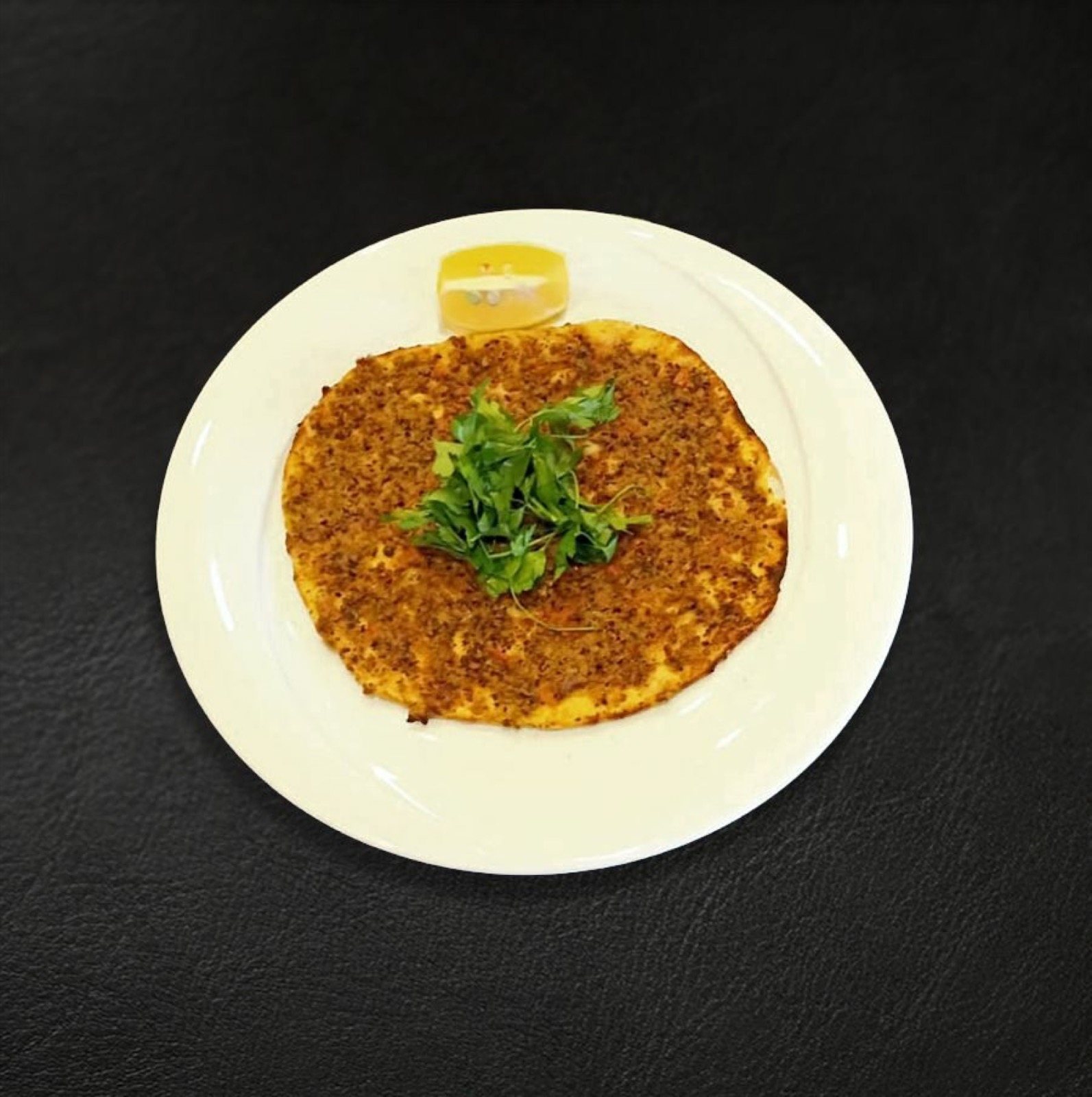 Beyaz tabakta lahmacun, üzerinde roka ve limon dilimi
