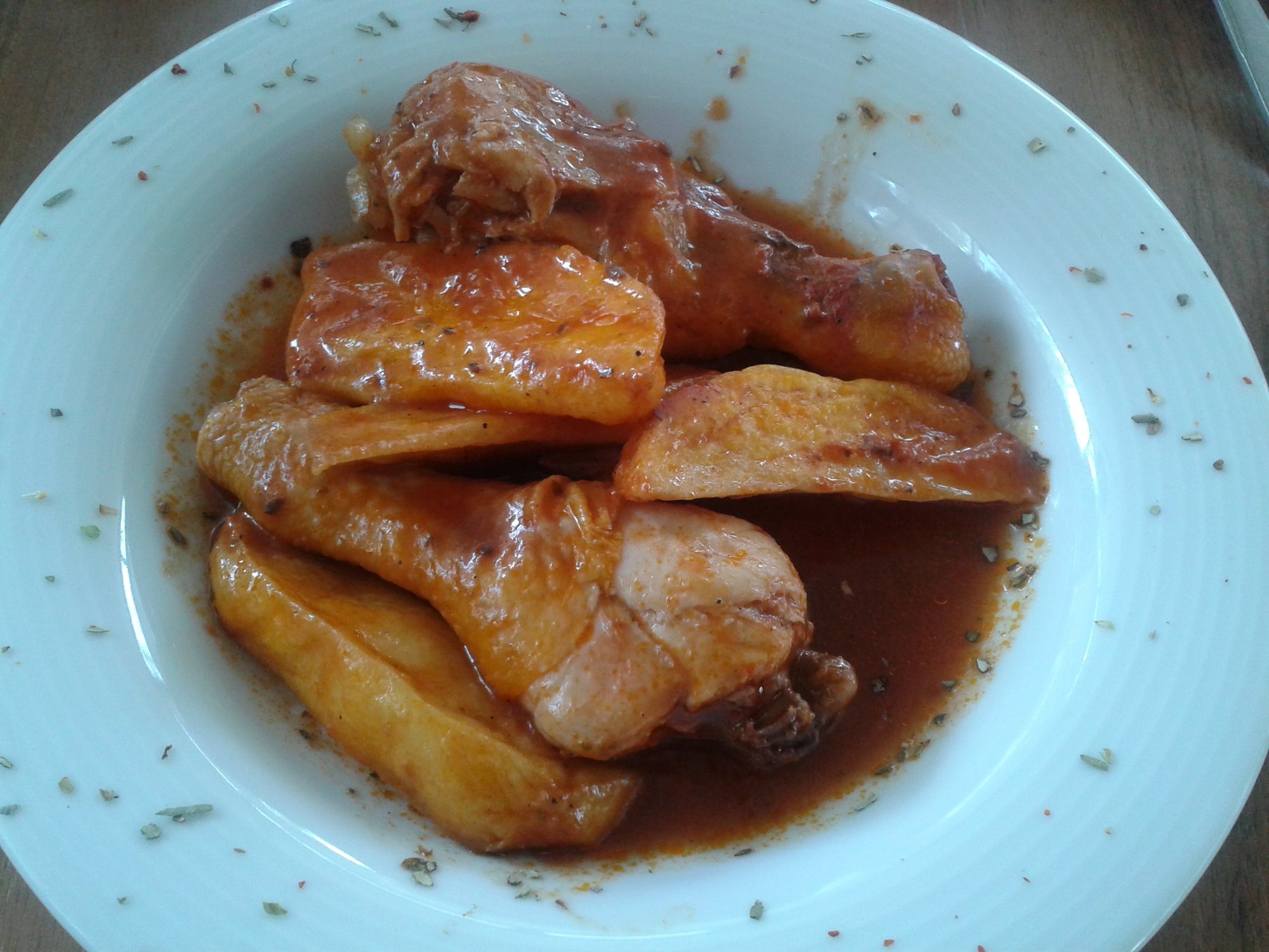Domates soslu fırında tavuk ve patates dilimleri, beyaz tabakta servis